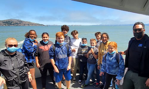 On a boat, in the ocean, can see Alcatraz in the background
