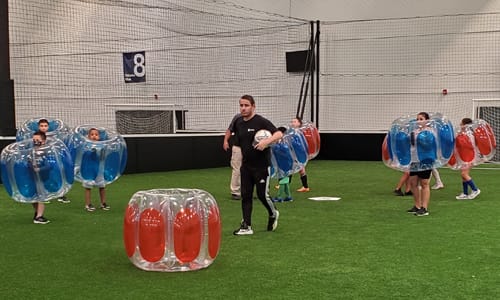 Kids playing indoor soccer in bubbles