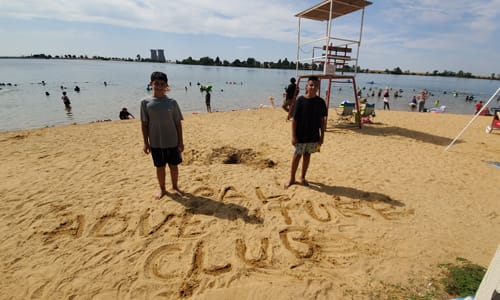 Kids writing in the sand at the beach