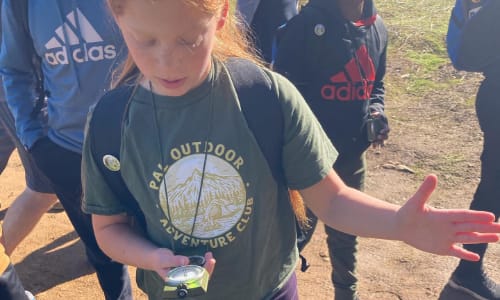 Girl using compass to find directions on trail