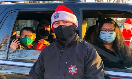 An officer posing with kids in their car.