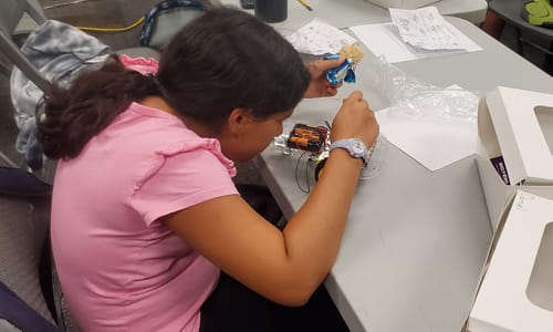 Girl putting together a robot for Robotics class